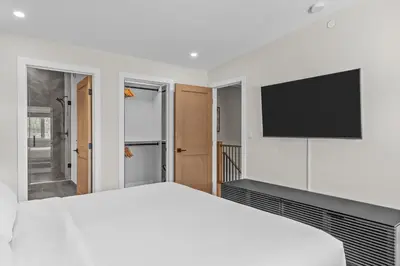 a bedroom with a white bed and a flat screen tv at Sisters Summit Villa by WeekAway Vacations in Canmore