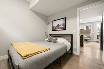 a bedroom with a bed with a yellow blanket on it at Heart of Hillhurst 1BR Home ! in Calgary