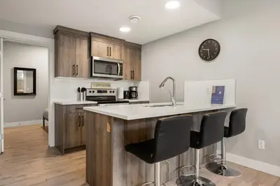 a kitchen with wooden cabinets and a counter with bar stools at Heart of Hillhurst 1BR Home ! in Calgary