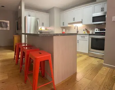 a kitchen with red stools and a kitchen with white cabinets at Whistler Gleneagle 27 in Whistler