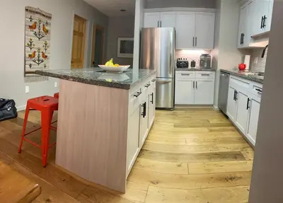 a kitchen with white cabinets and a wooden floor at Whistler Gleneagle 27 in Whistler