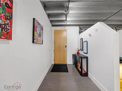 a hallway with white walls and a wooden door at Urban Pop Loft, Near ICE District, UG Parking in Edmonton