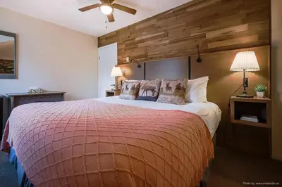 a bedroom with a large bed with a wooden wall at Entire Lovely Townhouse Mountain View! in Canmore