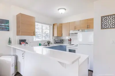 a white kitchen with a large white counter top at Entire Lovely Townhouse Mountain View! in Canmore