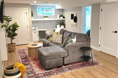 a living room with a gray couch and a rug at Boho Bliss - Just steps away from the Hospital in Prince George