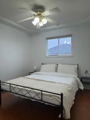 a bedroom with a bed with a ceiling fan at Spacious Getaway in Surrey in Surrey