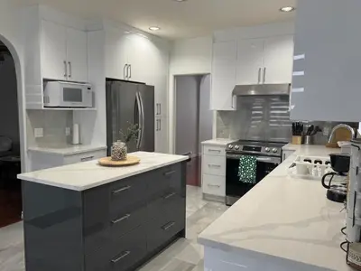 a kitchen with white cabinets and a black refrigerator at Spacious Getaway in Surrey in Surrey