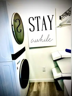 a bathroom with a toilet and a sign that says stay awhile at Humble Living in Edmonton