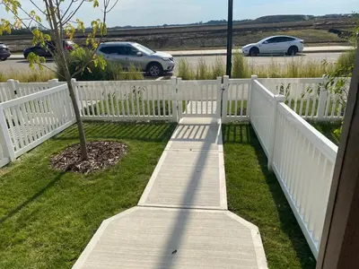 a white fence with a tree in the grass at Humble Living in Edmonton