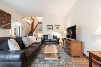 a living room with a black leather couch and a tv at Blueberry Hill Estates 3180 by Outpost Whistler in Whistler