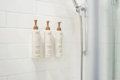 three shampoo bottles are sitting on a rack in a shower at Blueberry Hill Estates 3180 by Outpost Whistler in Whistler