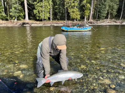 a man is holding a fish in the water at Brickwood Cabin in Sayward