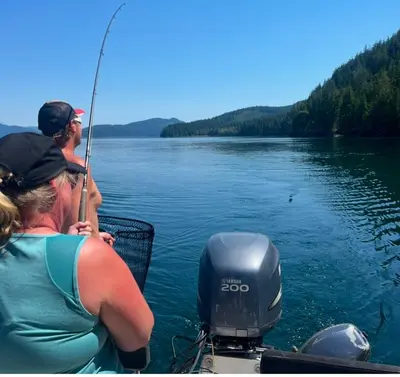 a man and woman fishing on a boat on a lake at Brickwood Cabin in Sayward