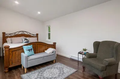 a bedroom with a bed and a chair at Brickwood Cabin in Sayward