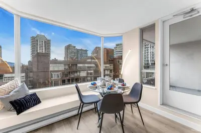 a dining room with a table and chairs and a large window at Beautiful City Two Beds Suite with Free Parking in Vancouver