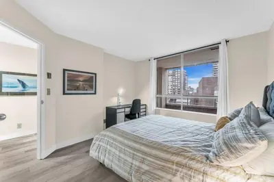 a bedroom with a bed and a large window at Beautiful City Two Beds Suite with Free Parking in Vancouver