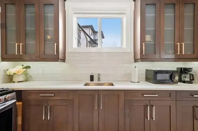 a kitchen with wooden cabinets and a sink and a window at Bright & Cozy 2-Bedroom Basement Suite in Chestermere