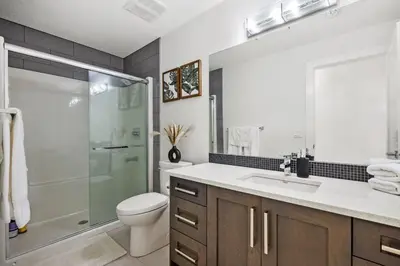 a bathroom with a shower and a toilet and a sink at Bright & Cozy 2-Bedroom Basement Suite in Chestermere