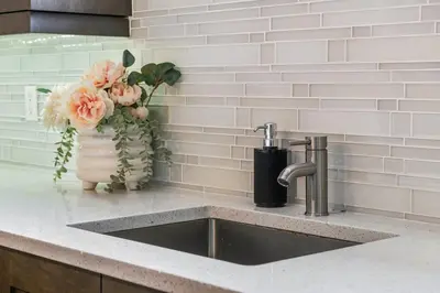 a kitchen counter with a sink and a vase of flowers at Bright & Cozy 2-Bedroom Basement Suite in Chestermere