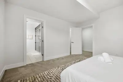 a white bedroom with a bed and a walk in shower at Bright & Cozy 2-Bedroom Basement Suite in Chestermere
