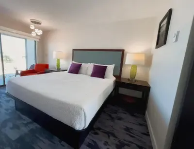 a bedroom with a large bed and a red chair at The Oceanside, a Coast Hotel in Sechelt