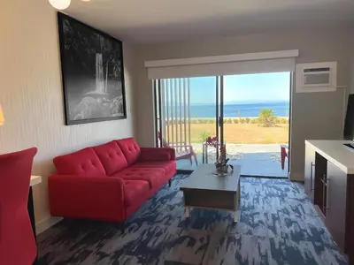 a living room with a red couch and a view of the ocean at The Oceanside, a Coast Hotel in Sechelt