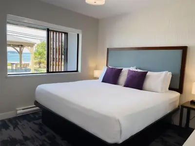 a bedroom with a large white bed with purple pillows at The Oceanside, a Coast Hotel in Sechelt