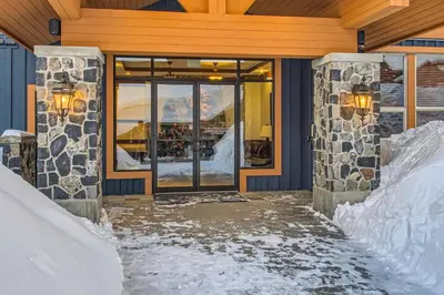 a building with snow in front of a glass door at Stonegate Resort Unit A206 in Kelowna