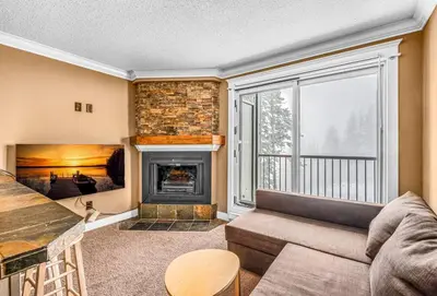 a living room with a couch and a fireplace at Winter Escape On Perfection - Ski In Out, Pool & Hot Tub in Big White