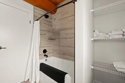 a bathroom with a white tub and a shower at The View Point Lodge Cozy Log House with Hot Tub in Vernon
