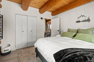 a bedroom with a large bed with white walls and wooden ceilings at The View Point Lodge Cozy Log House with Hot Tub in Vernon