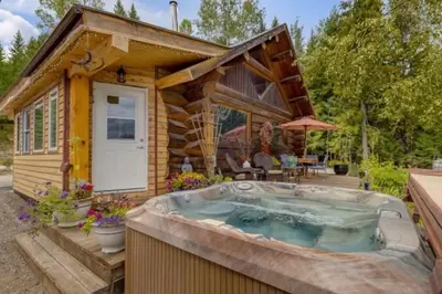 a log cabin with a hot tub in front of it at Authentic lofted log cabin with hot tub in Kelowna