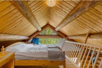 a bedroom in a log cabin with a bed in it at Authentic lofted log cabin with hot tub in Kelowna