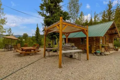 a log cabin with a picnic table and a tent at Authentic lofted log cabin with hot tub in Kelowna
