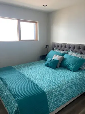 a bedroom with a large bed with blue pillows at Lakefront Nest Beach House Suite in Penticton