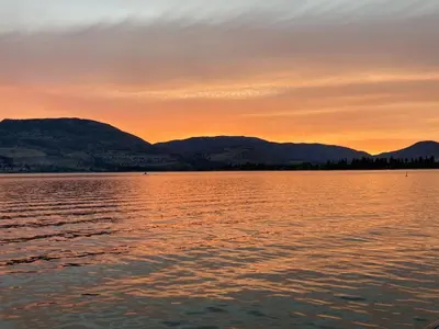 a sunset over a large body of water at Lakefront Nest Beach House Suite in Penticton