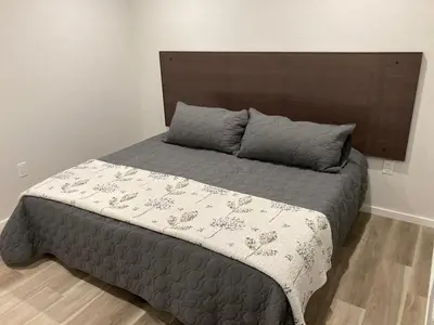 a bedroom with a large bed with a wooden headboard at Lakefront Nest Beach House Suite in Penticton