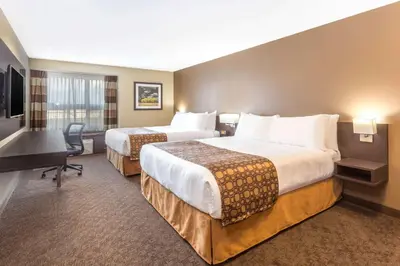 a hotel room with two beds and a desk at Microtel Inn & Suites by Wyndham Whitecourt in Whitecourt