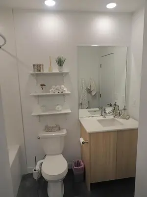 a bathroom with a toilet and a sink and a mirror at Modern Cozy Nest in Calgary