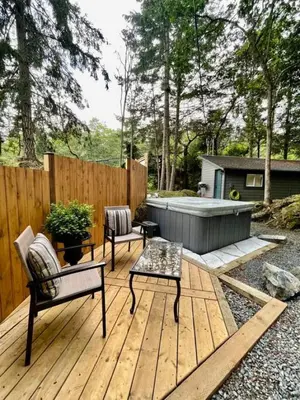 a wooden deck with a bench and a hot tub at Cozy Cabana with Large Private Outdoor Hot Tub in Nanoose Bay