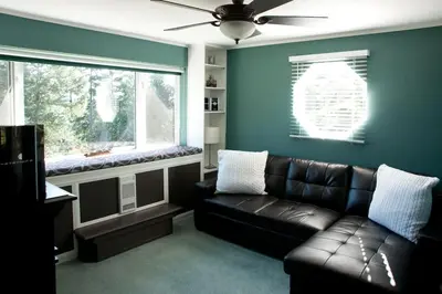 a living room with a leather couch and a window at Oceanview Guest Suite with Large 2 Person Soaker Tub in Nanoose Bay
