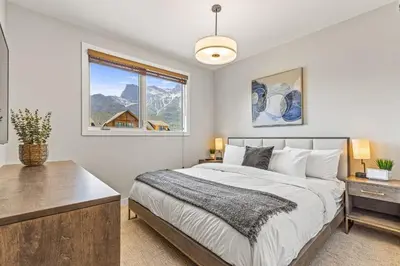 a bedroom with a large bed and a window at Elevated Mountain Living 2BD Spring Creek Unit in Canmore