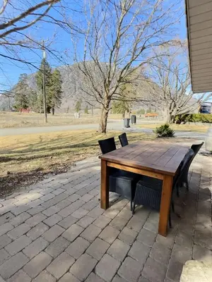 a wooden picnic table with two chairs around it at Taurean Vines Guest house in Keremeos