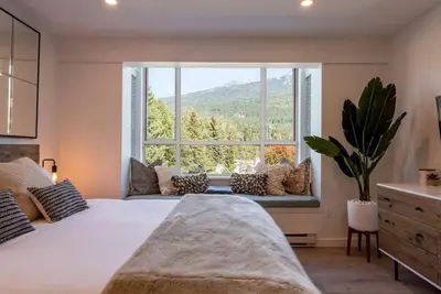 a bedroom with a large bed and a large window at Location with Views - 2BDR Penthouse Whistler Village in Whistler