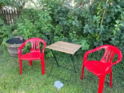 two red chairs and a table in the grass at Vancouver Central Green Studio in Vancouver