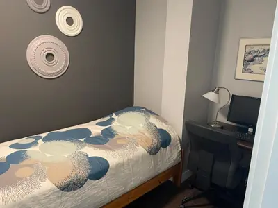 a bedroom with a bed and a desk with a computer at Hastings Sunrise Experience in Vancouver