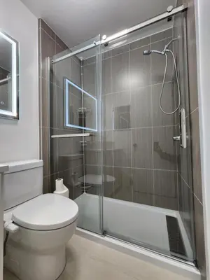 a bathroom with a toilet and a glass shower at 2-bed house for downtown, stampede & mountains in Calgary