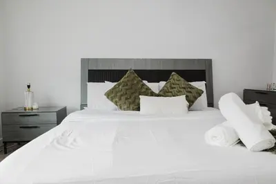 a white bed with white sheets and pillows at Executive Modern Family Haven for Short Stays in Edmonton