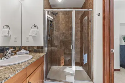 a glass shower in a bathroom with a sink at Skyline Suite Downtown Canmore Stay in Canmore