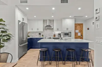 a kitchen with white cabinets and blue counter stools at Stylishly Renovated Spring Creek Retreat in Canmore